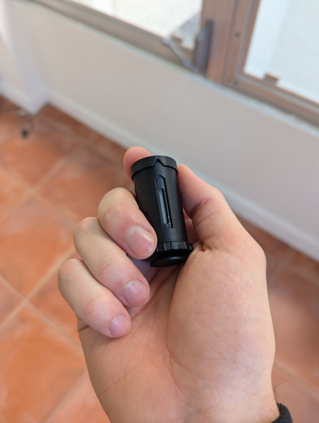 DoseMate Spin Core Black portable powder dispenser held in hand for size comparison